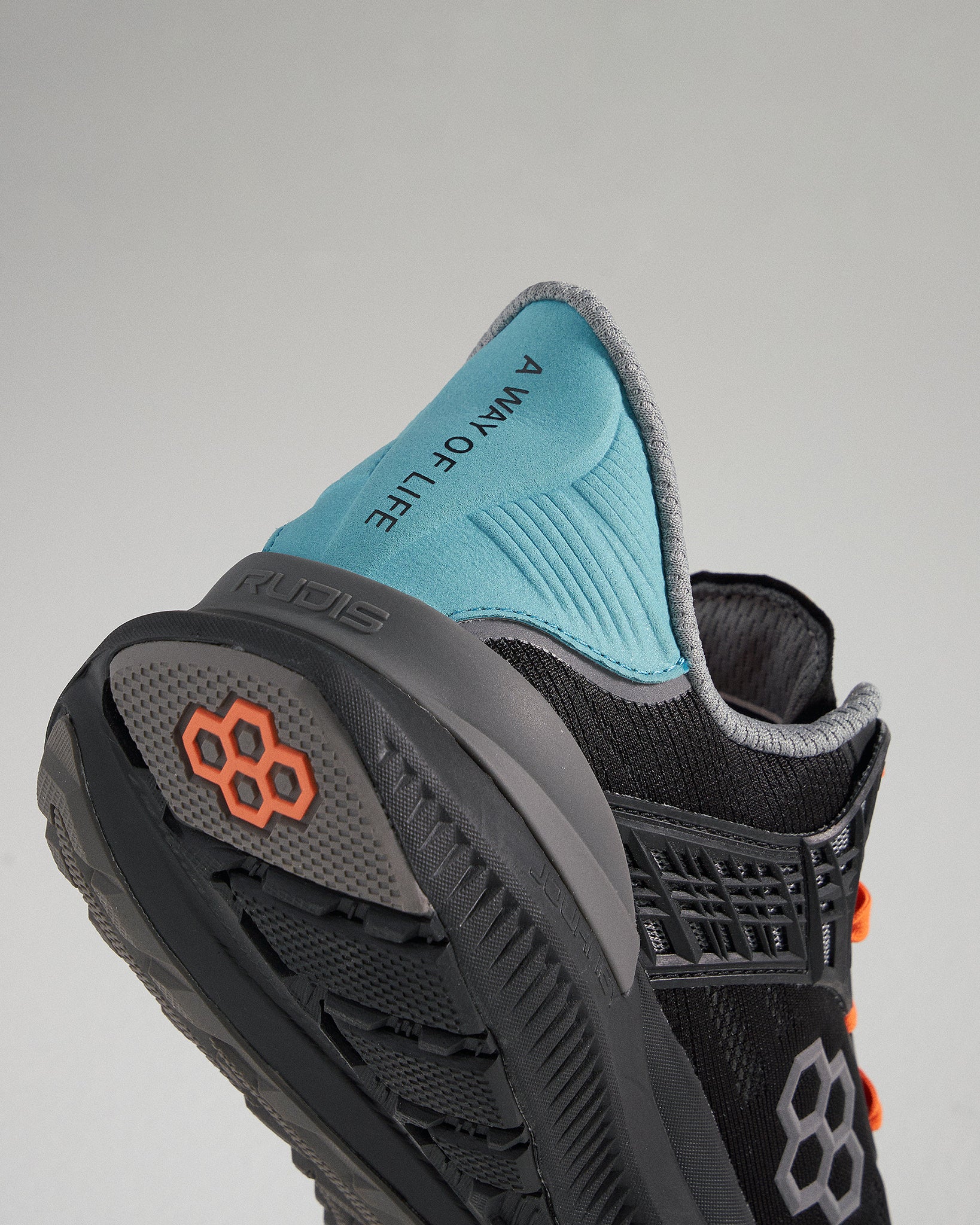 A close-up view of a black and teal athletic shoe highlighting its design features and text that reads A WAY OF LIFE