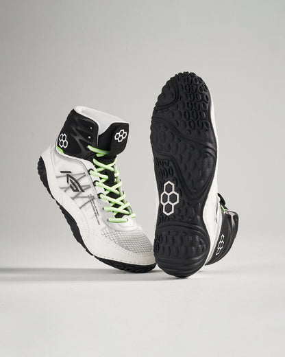 This image features high-top white athletic shoes with black accents and vibrant green laces emphasizing a modern design and intricate sole pattern for enhanced performance