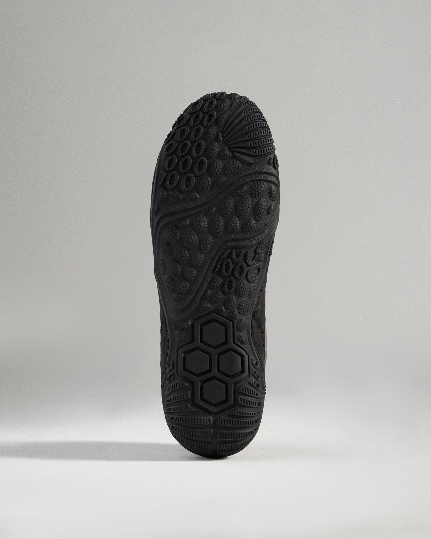 A close-up view of the intricate tread pattern on a black athletic shoe sole