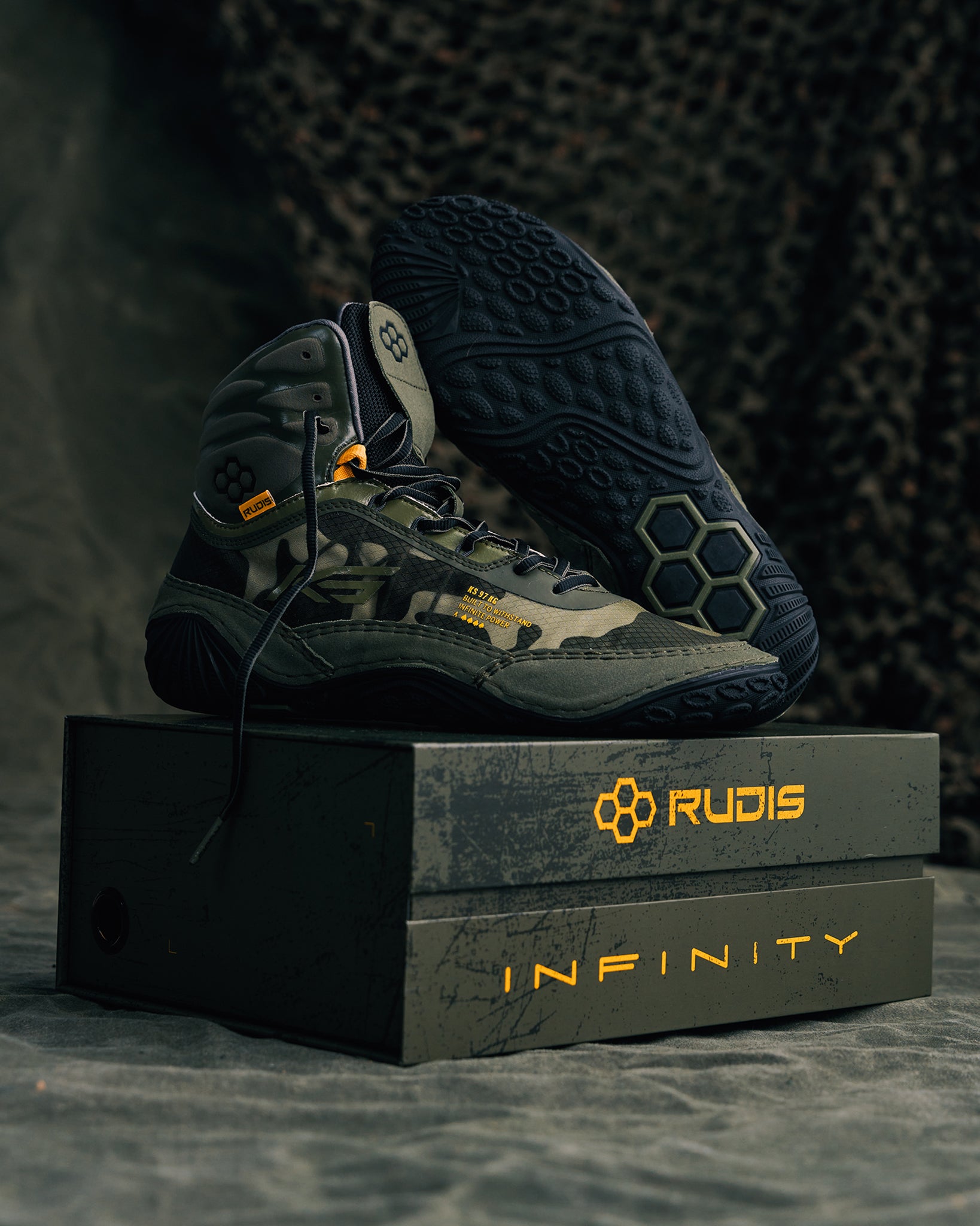 A pair of camo-patterned wrestling shoes displayed on a box highlighting their design and brand details