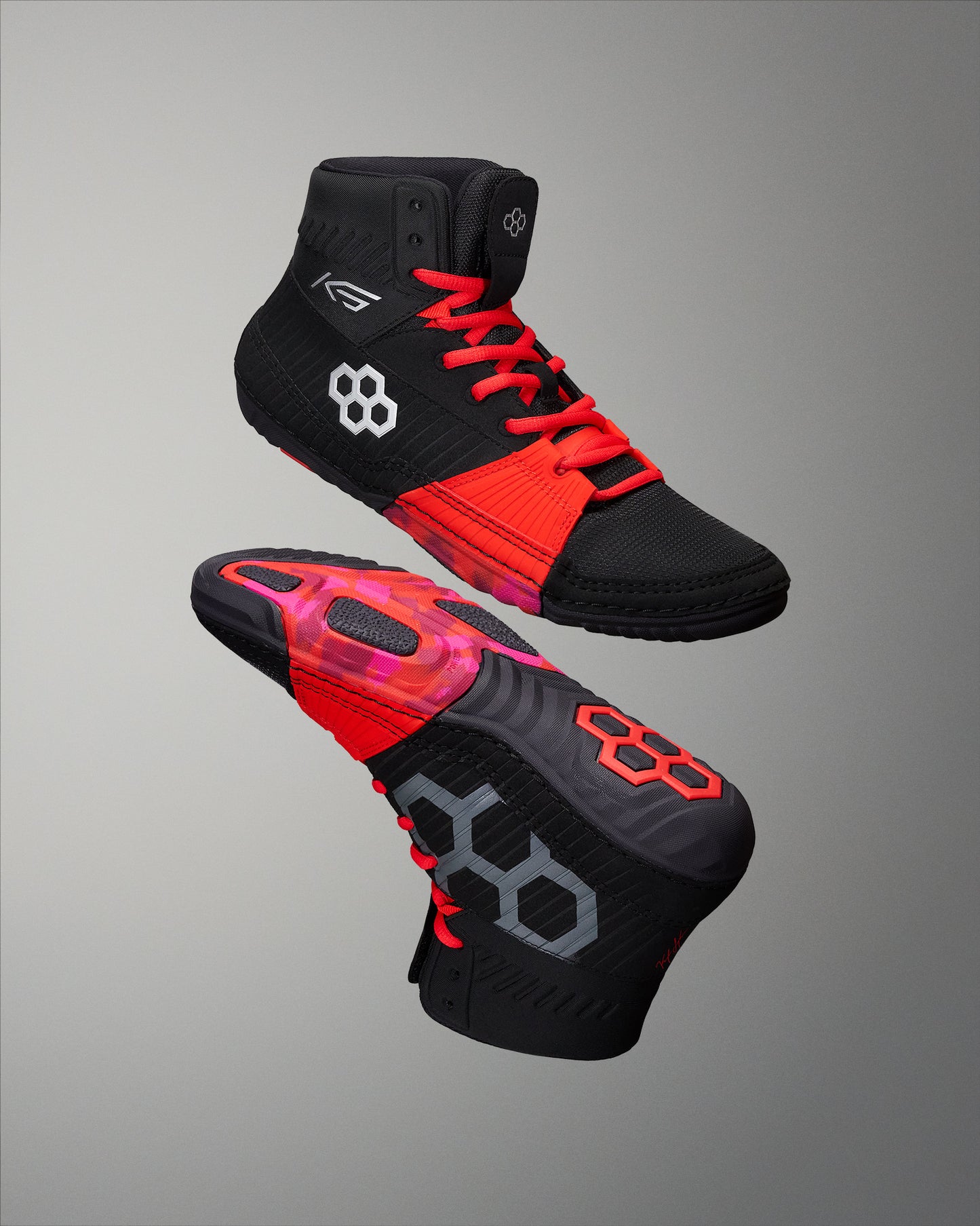 Black and red RUDIS wrestling shoe with a segmented outsole, emphasizing traction and athletic design.