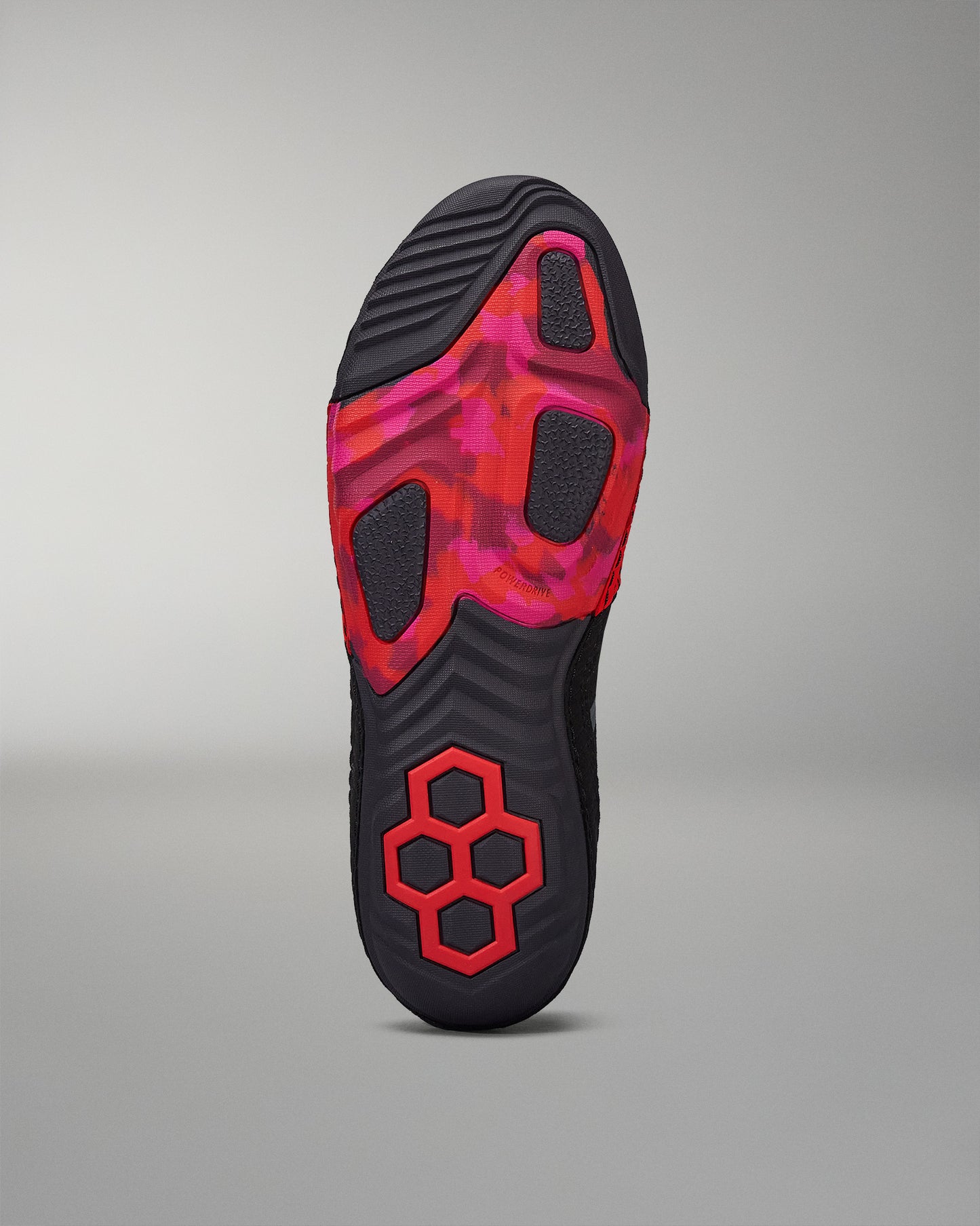 Bottom sole view of a black RUDIS wrestling shoe with red accents and a segmented outsole for traction.