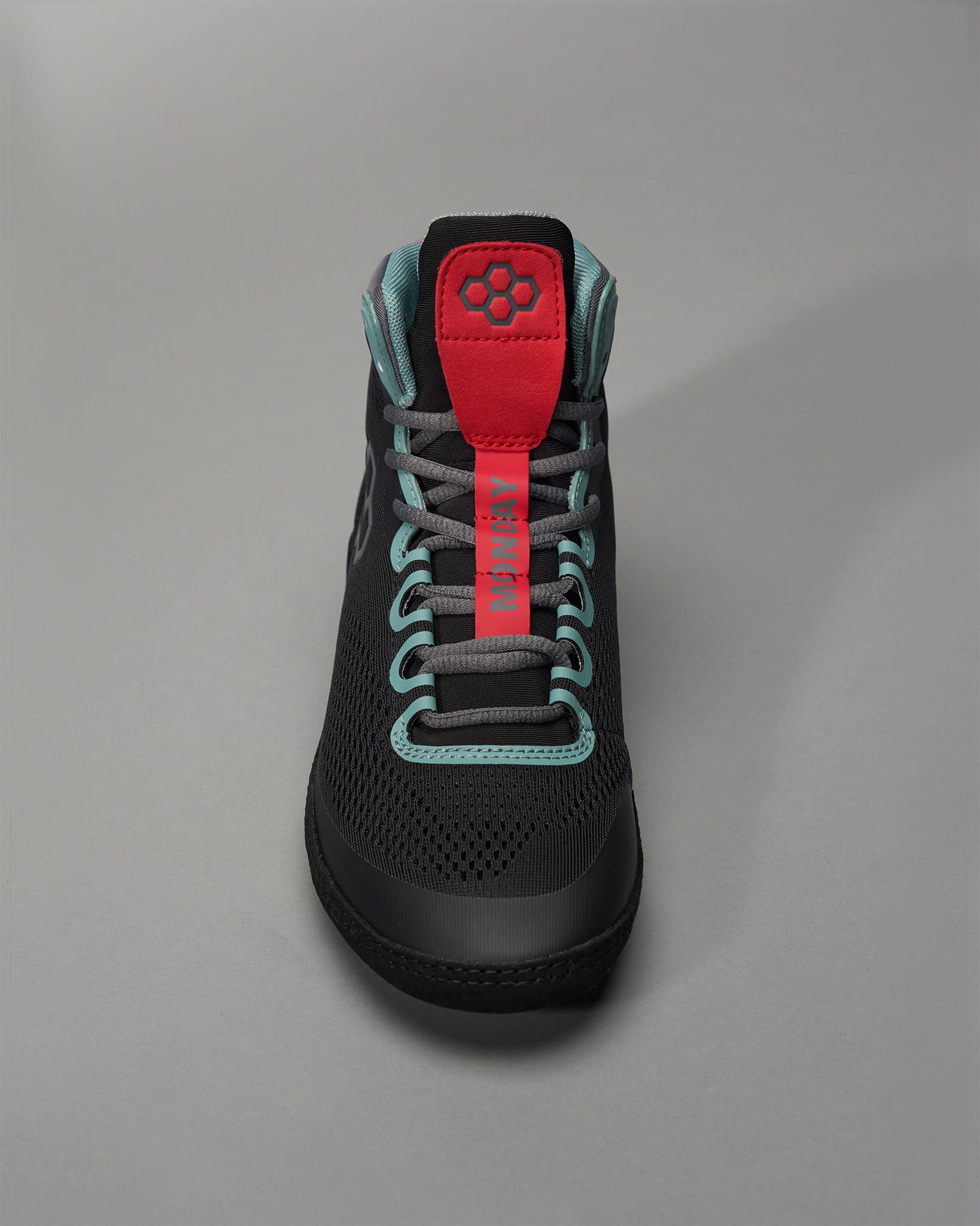 A modern black athletic shoe with teal accents and a bold red label reading MONDAY on the tongue designed for both style and performance