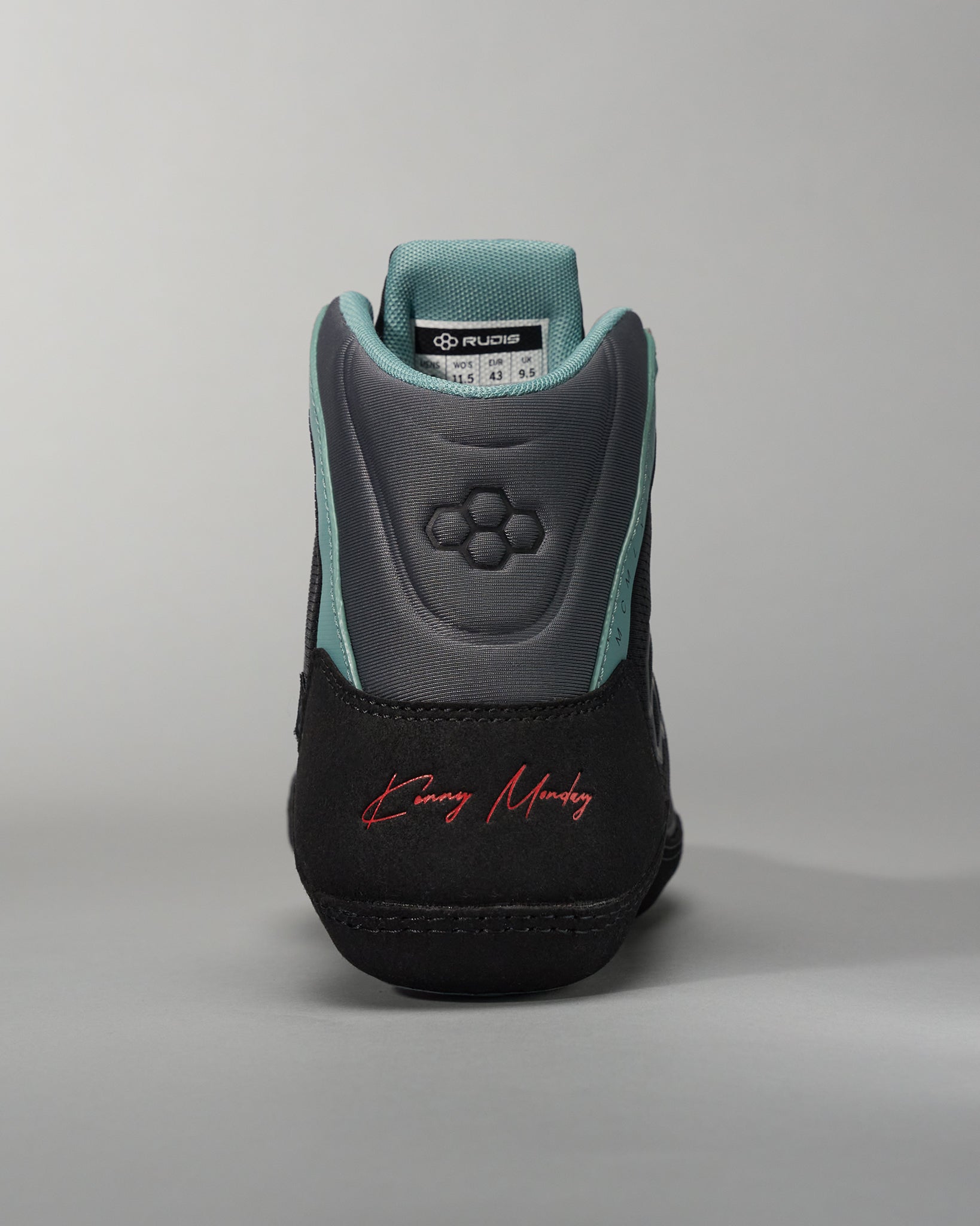 This image displays a black and teal athletic shoe designed for performance featuring a textured heel and a signature on the back