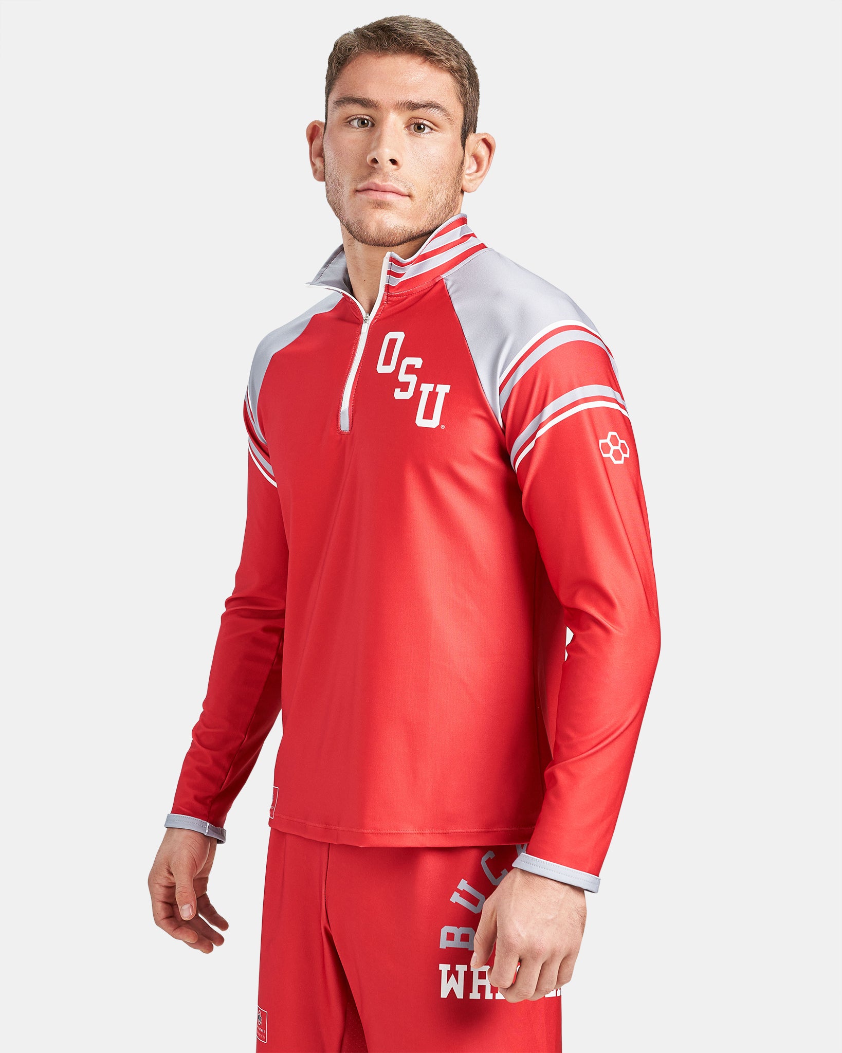 A young man models a red long-sleeve athletic top with OSU branding featuring a half-zip design and reflective gray accents paired with matching red shorts