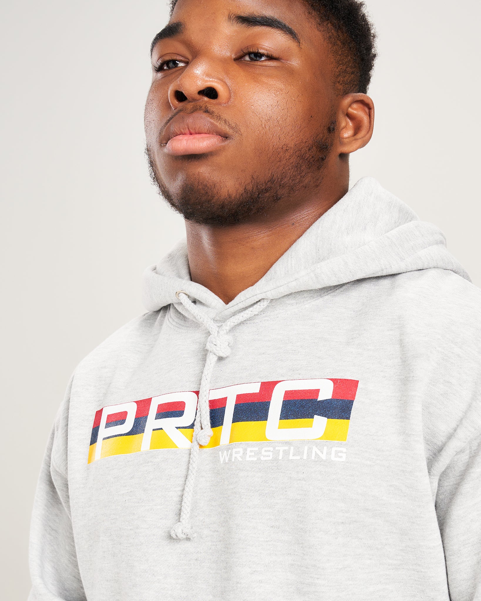 A young man wearing a gray hoodie with the PRTC WRESTLING logo showcasing a confident expression and sporting short hair