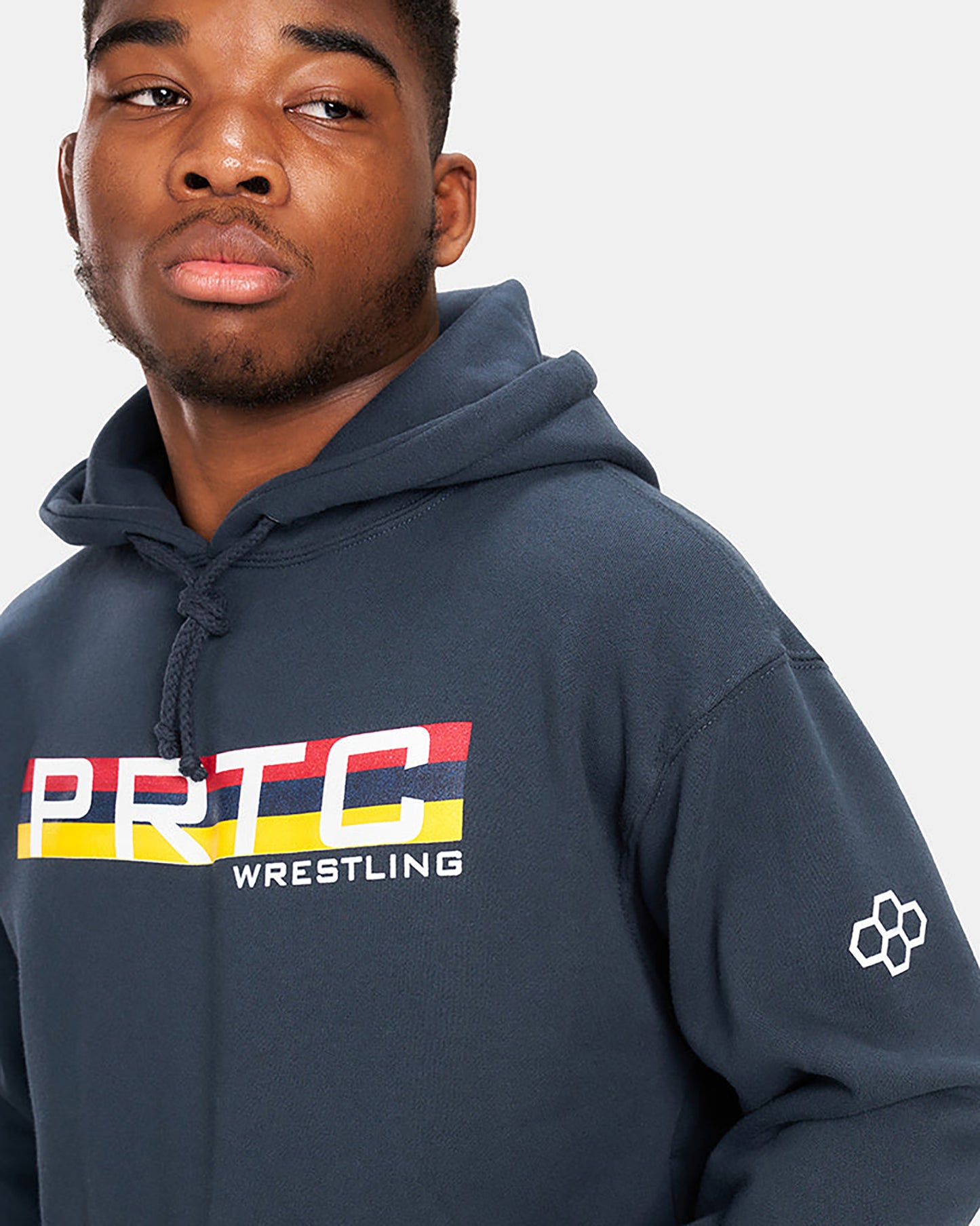 A young man wearing a navy hoodie with a bold PRTC WRESTLING graphic displaying vibrant colors and a modern design