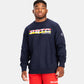 A young man poses in a navy sweatshirt featuring a bold graphic design that highlights PRTC WRESTLING paired with bright red athletic shorts for a casual sporty look