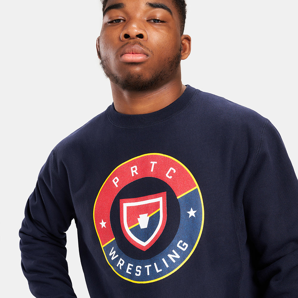 An individual wearing a navy blue sweatshirt featuring a bold circular graphic design related to wrestling