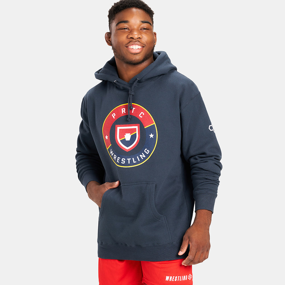 A young male athlete poses in a navy blue hoodie with a prominent wrestling logo highlighting a casual and sporty look