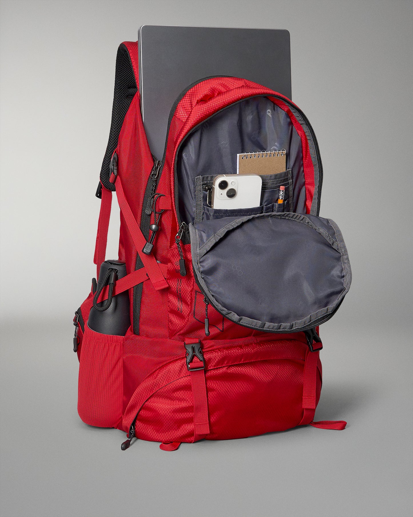 A vibrant red backpack features multiple compartments including space for a laptop a phone and a water bottle highlighting its practicality for students or travelers