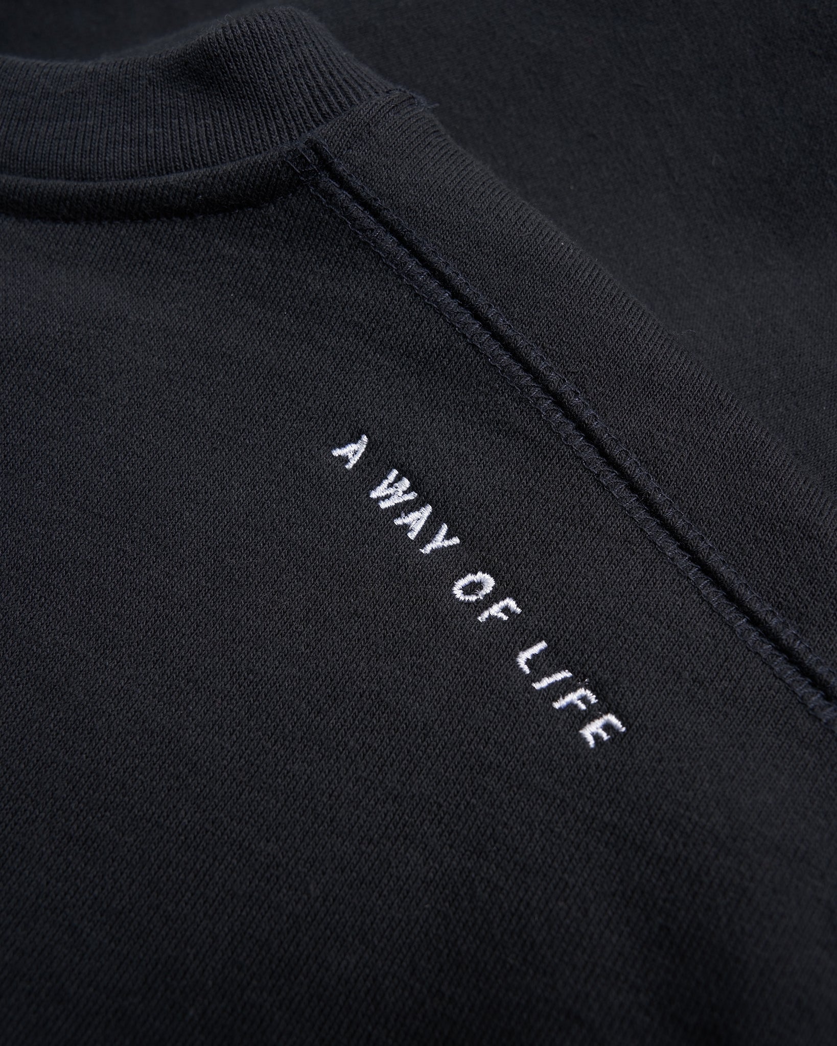 Black sweatshirt featuring the embroidered phrase A WAY OF LIFE in white text on the back