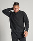 A young man poses confidently in a stylish black sweatshirt against a neutral background showcasing a modern casual look