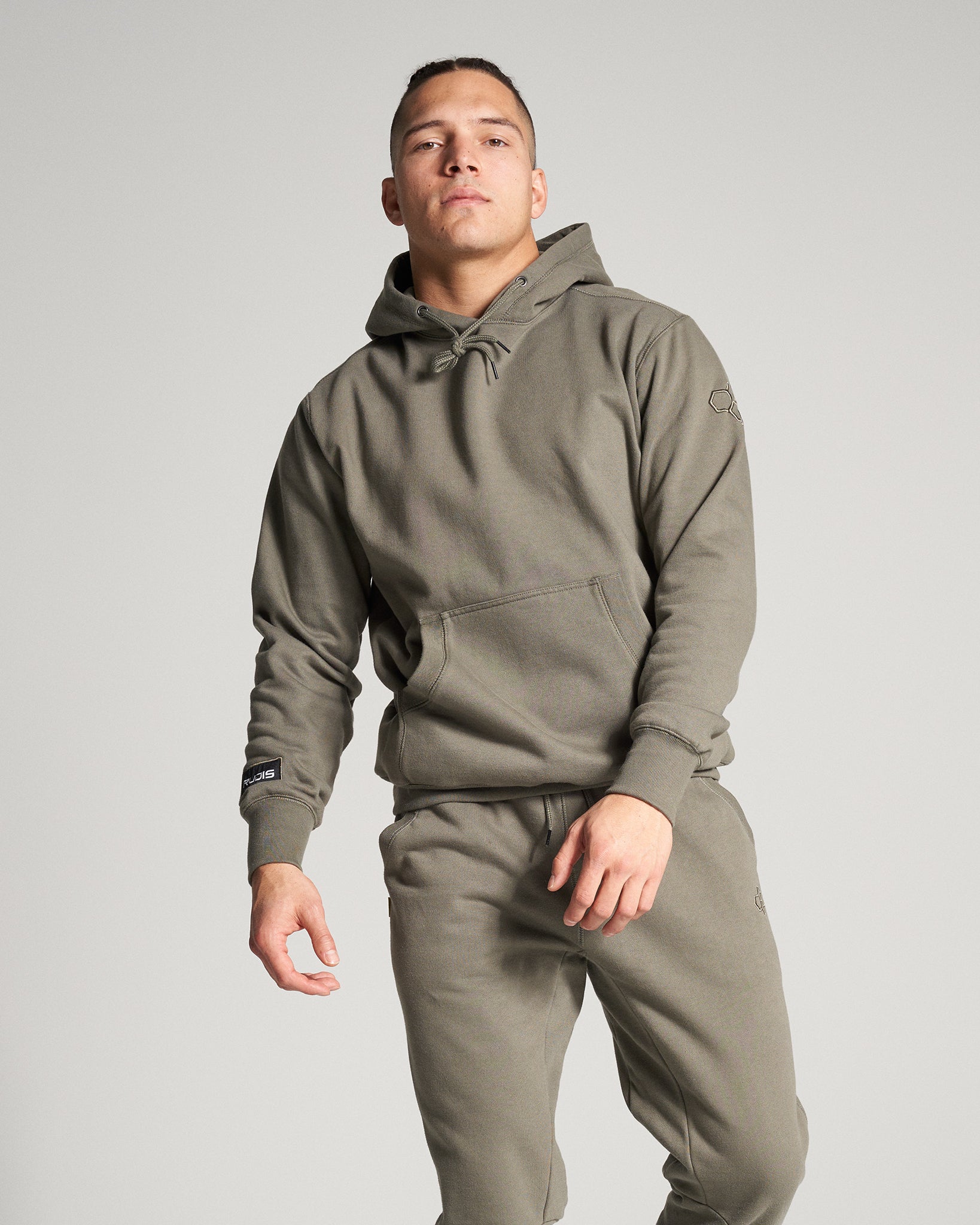 A man poses confidently in a comfortable olive-green hoodie and matching sweatpants showcasing a relaxed yet stylish athleisure look