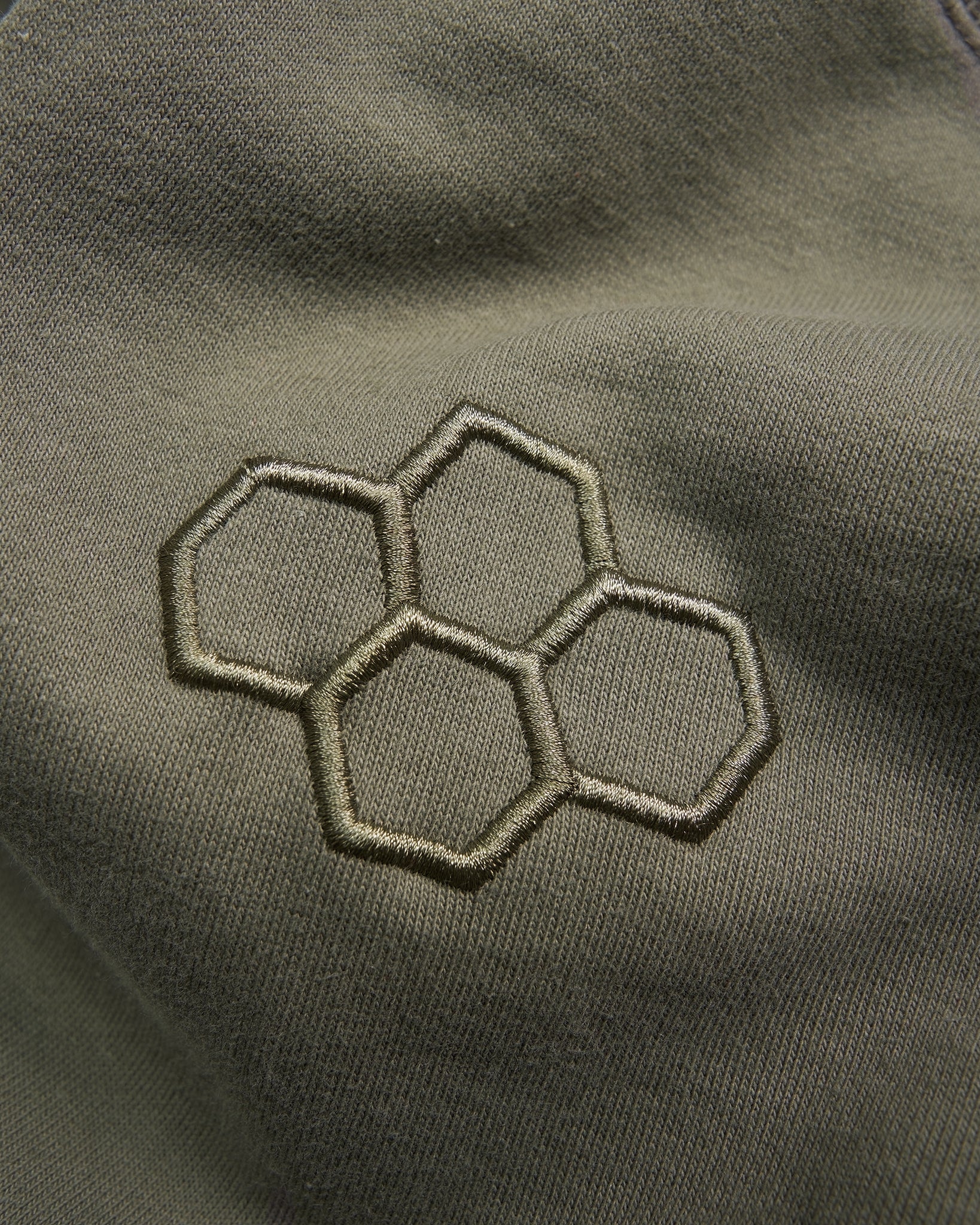 An embroidered hexagonal pattern in olive-green fabric highlighting a modern design aesthetic