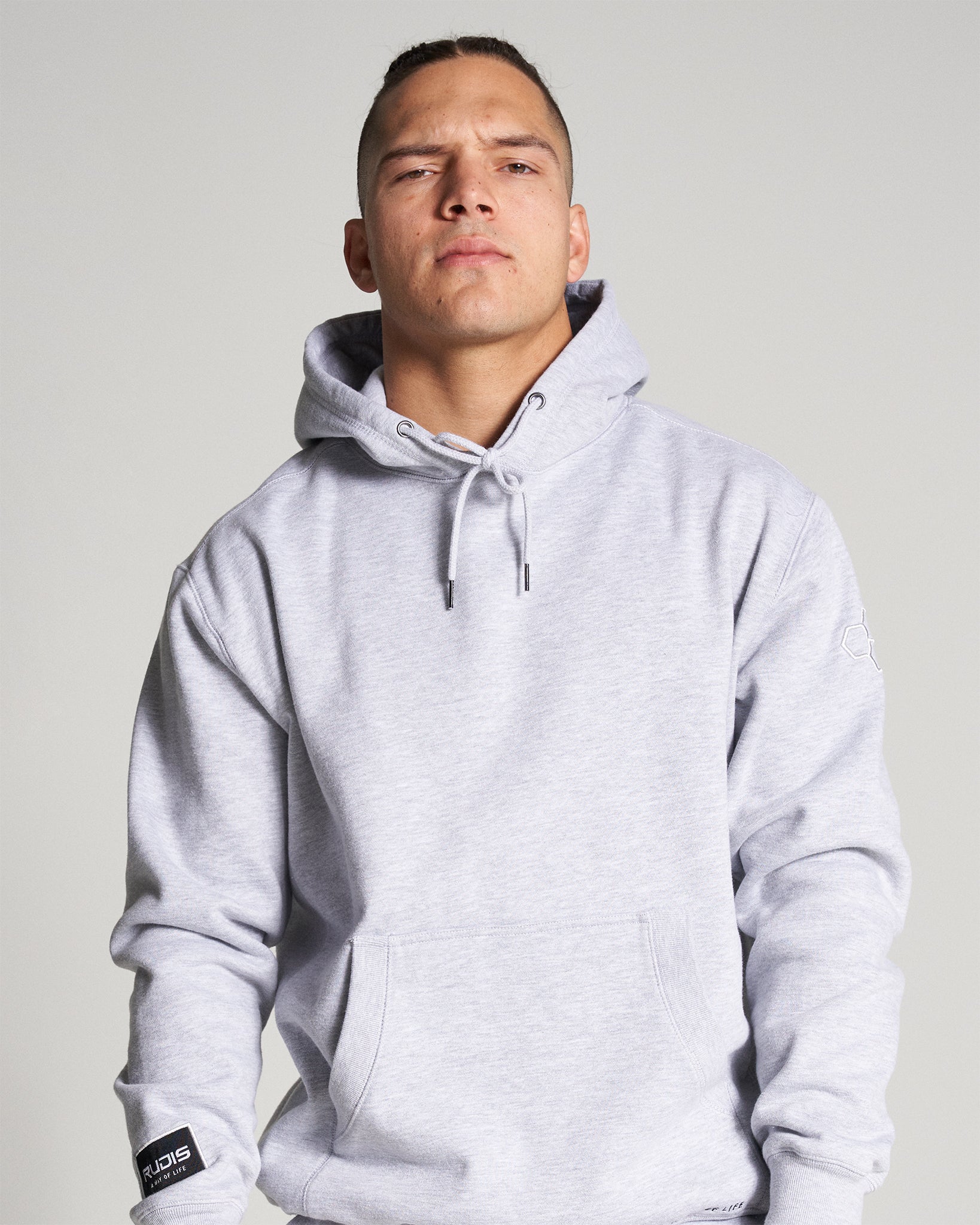 A man wearing a gray hoodie with a confident expression showcasing casual yet stylish athletic wear