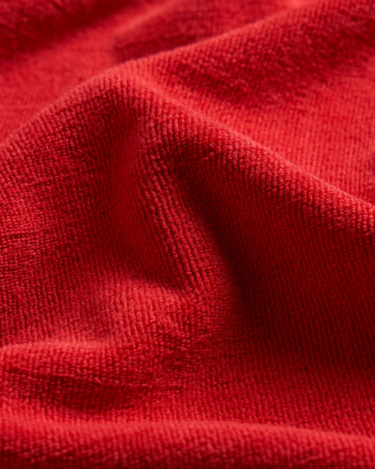 Close-up view of a red textured fabric showcasing soft and plush fibers highlighting its warm and inviting look