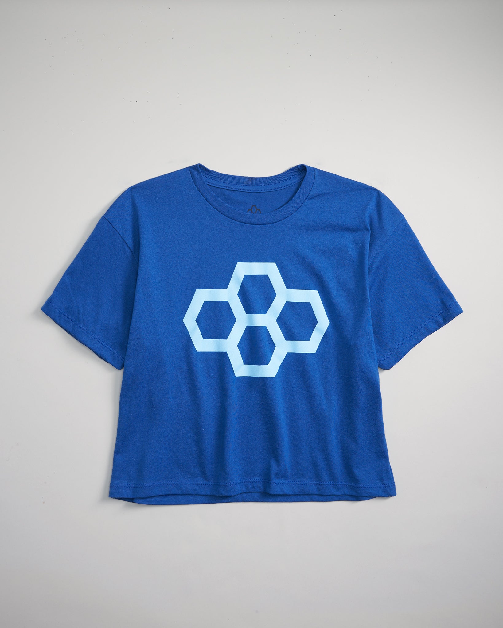 A vibrant blue cropped t-shirt featuring a large geometric honeycomb pattern in light blue on the front