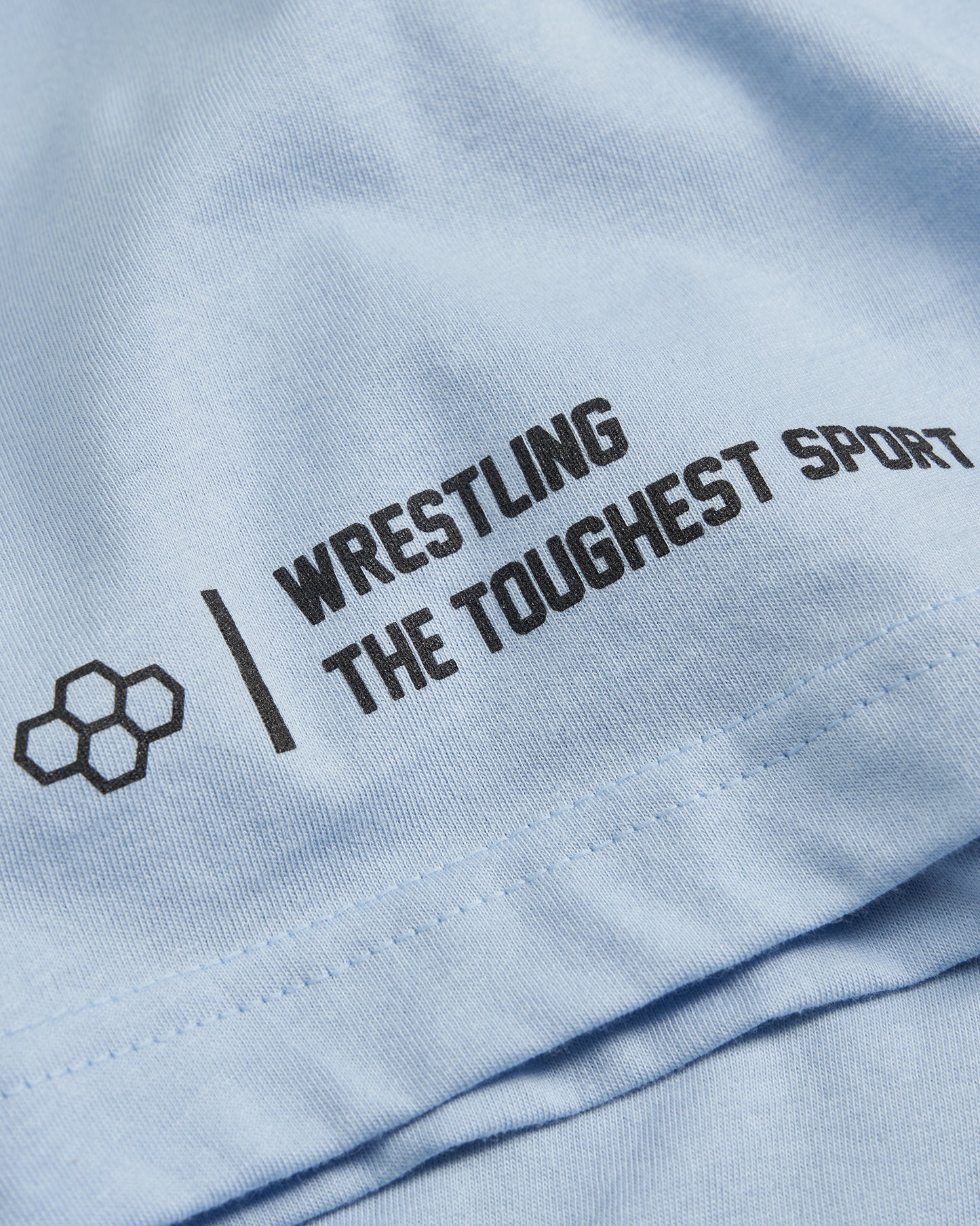 A light blue fabric featuring bold black text that states WRESTLING THE TOUGHEST SPORT accompanied by a geometric design element