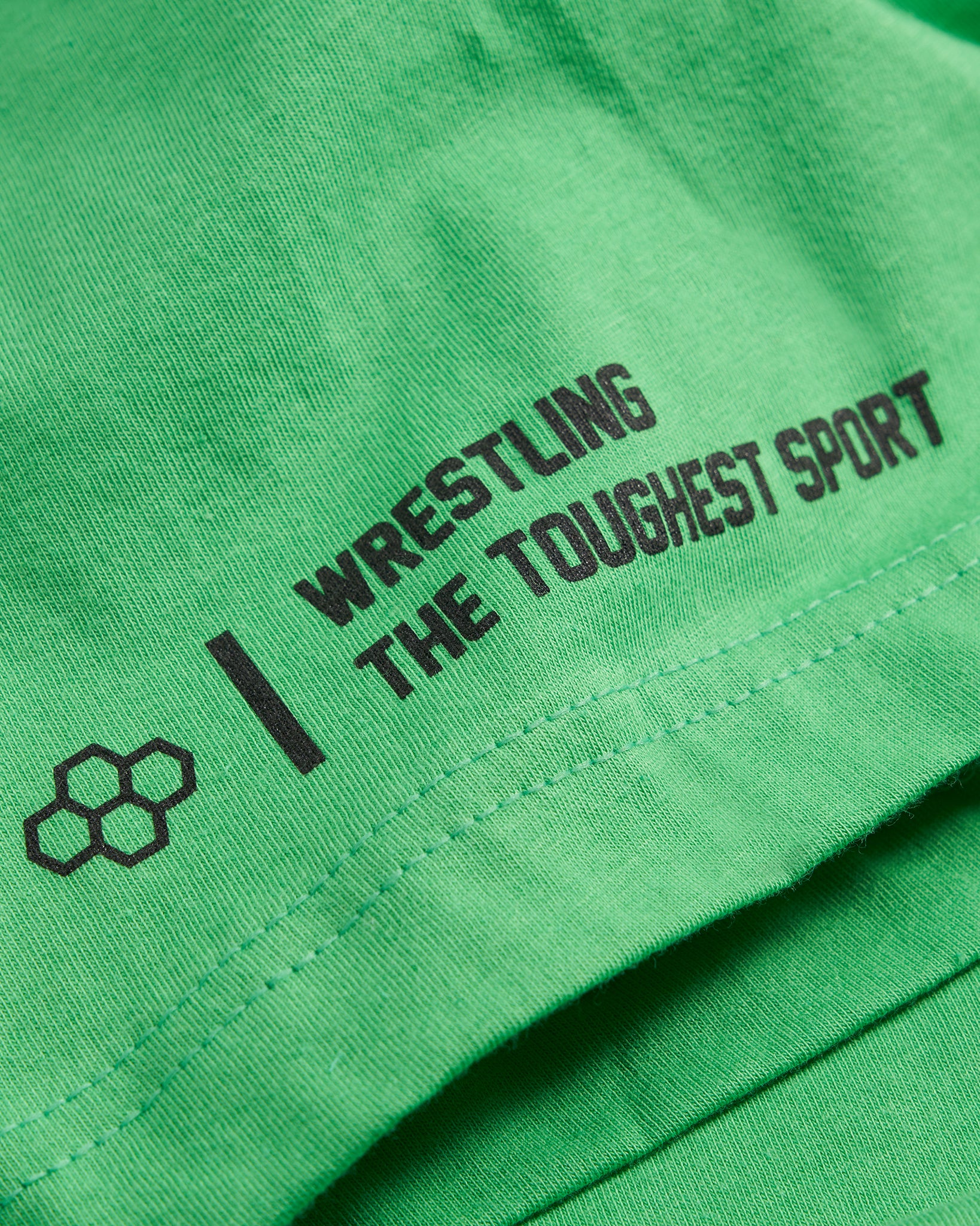 A close-up of a green t-shirt featuring bold black text proclaiming WRESTLING THE TOUGHEST SPORT