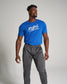 A fit man modeling a bright blue T-shirt with RUDIS written across the chest and gray athletic pants set against a neutral background