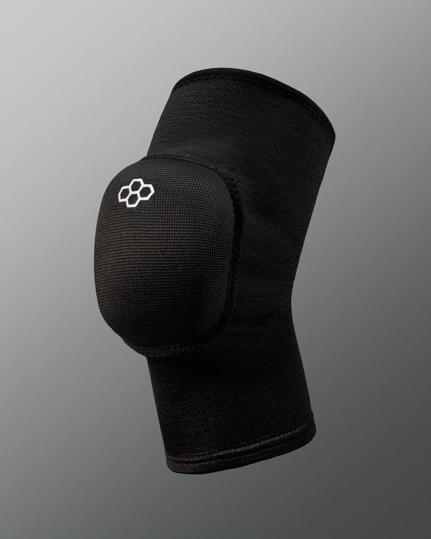 A black knee pad with a rounded protective cap and logo offers support for athletes, featuring breathable fabric and a minimalist design against a soft gray background.