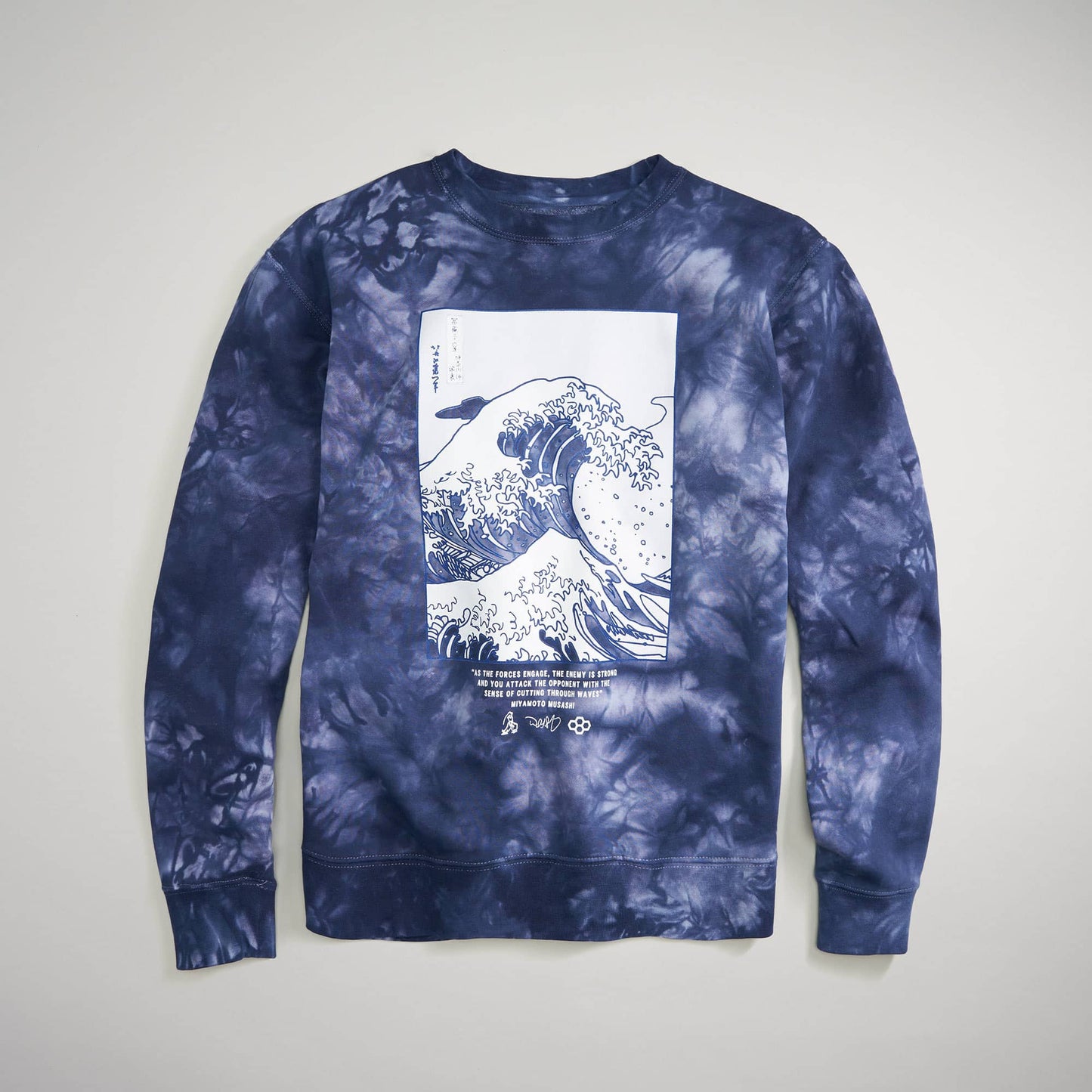 A stylish navy tie-dye sweatshirt featuring a prominent graphic of a wave above a quote about the ocean