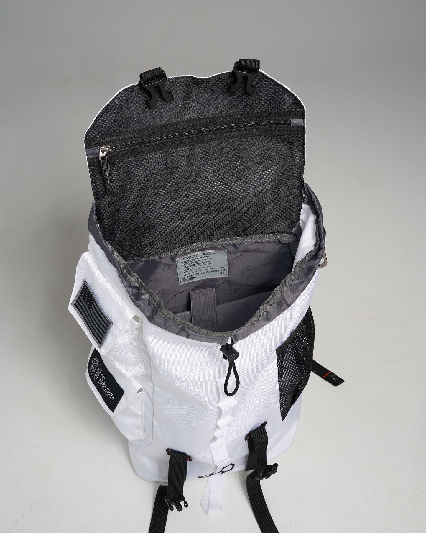 A white backpack with black accents featuring an open top showing its spacious interior and organizational pockets