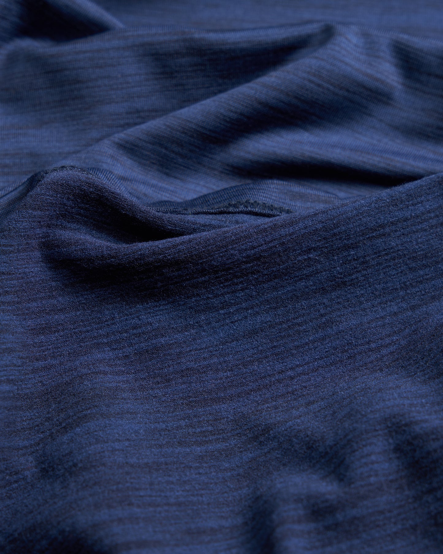 A close-up view of soft navy blue fabric with gentle folds showcasing its texture and depth