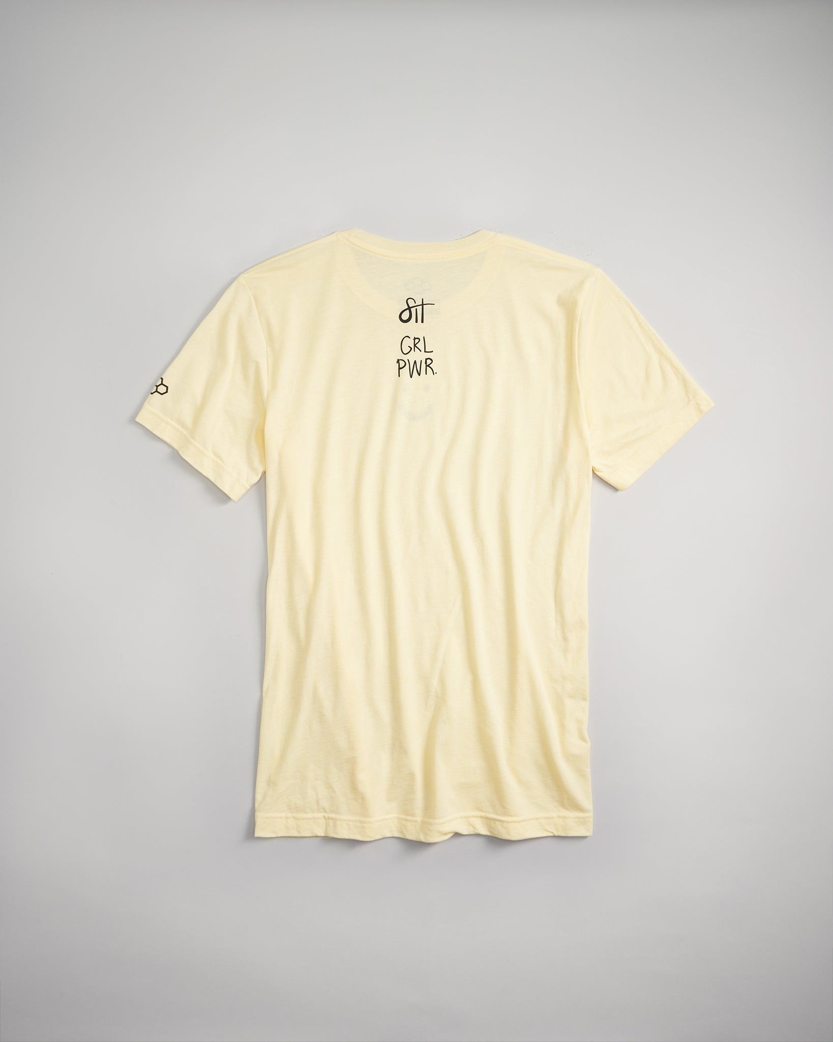 A light yellow t-shirt featuring the text SIT GRL PWR printed on the back