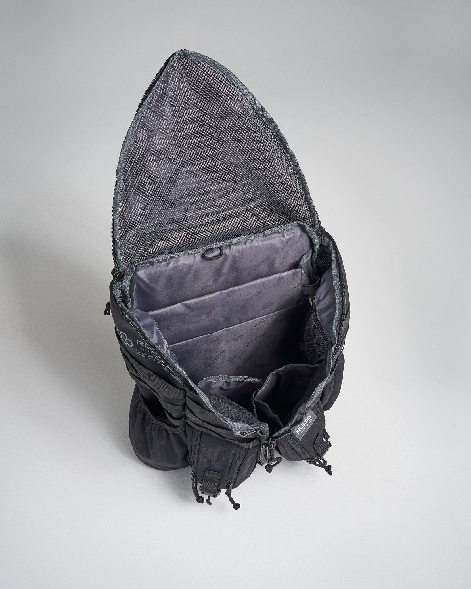 An open black backpack with multiple compartments showcasing a roomy interior and a mesh pouch at the top