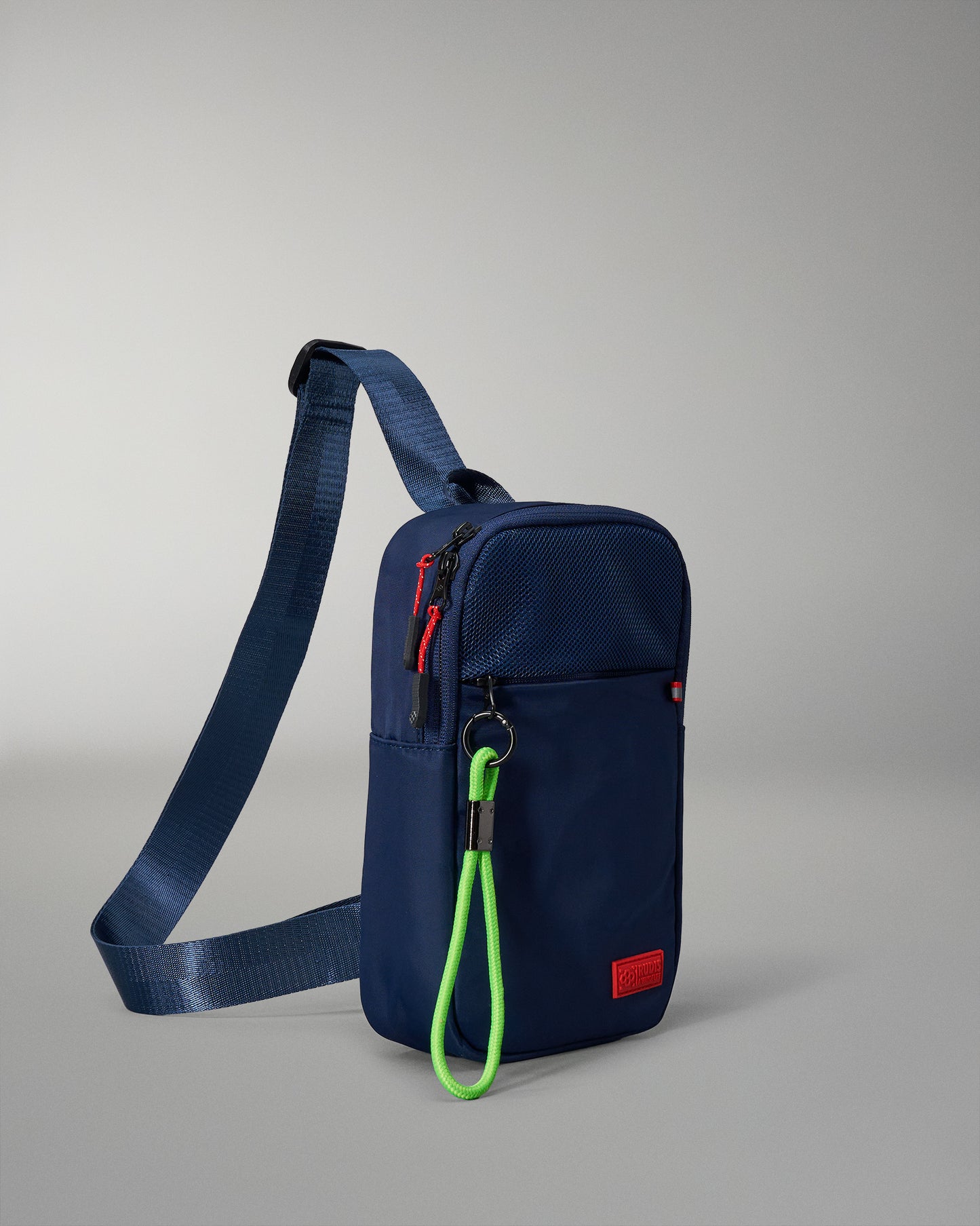 A navy crossbody bag with a zippered top and vibrant green zipper pull, offering secure storage and an adjustable strap for comfort against a light gray background.