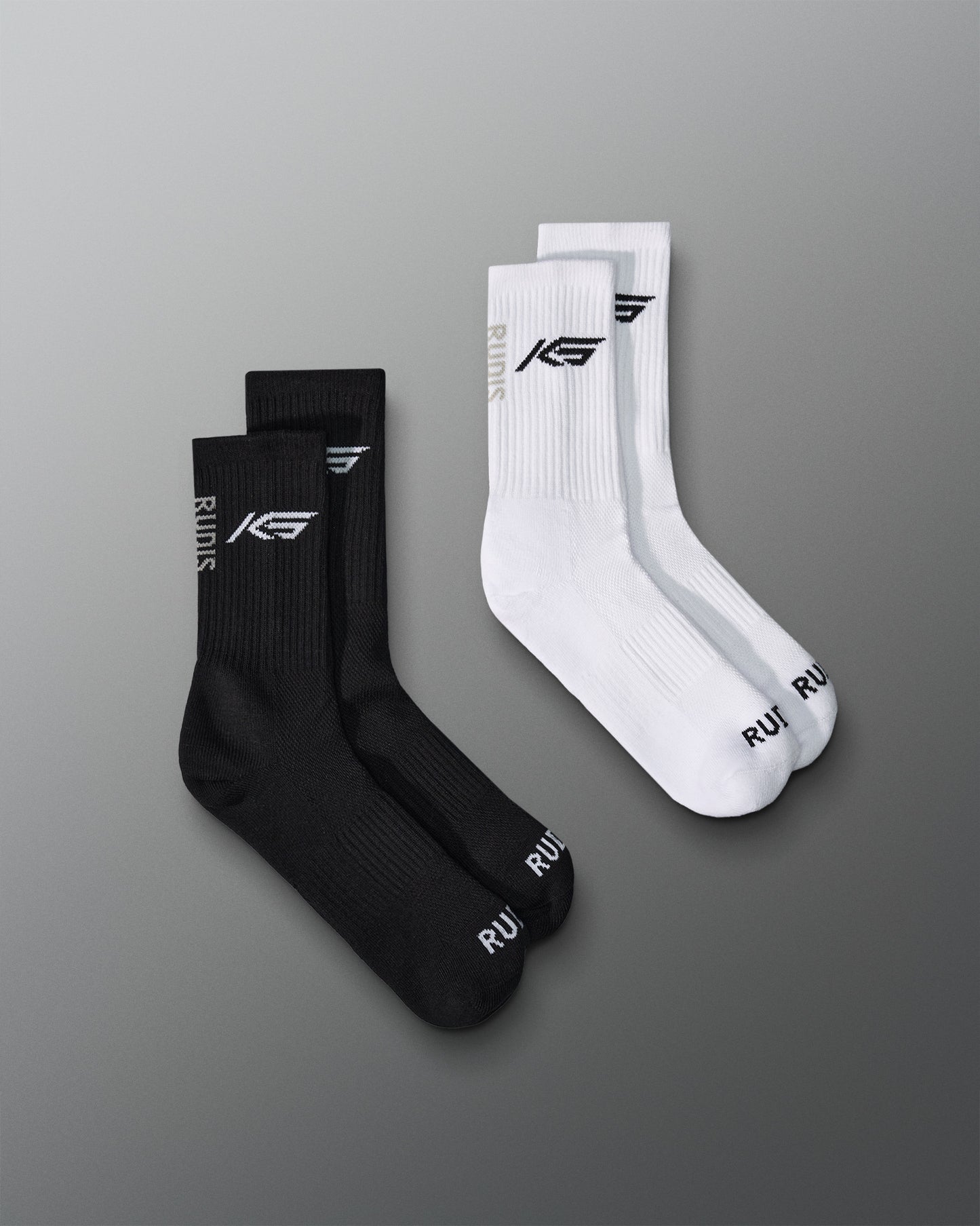 Two pairs of socks, black and white, featuring KS RUDIS logo and RUDIS Word mark on toes of cotton socks.