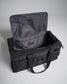 A black utility duffel bag with an open zipper top featuring a mesh pocket and branded label inside