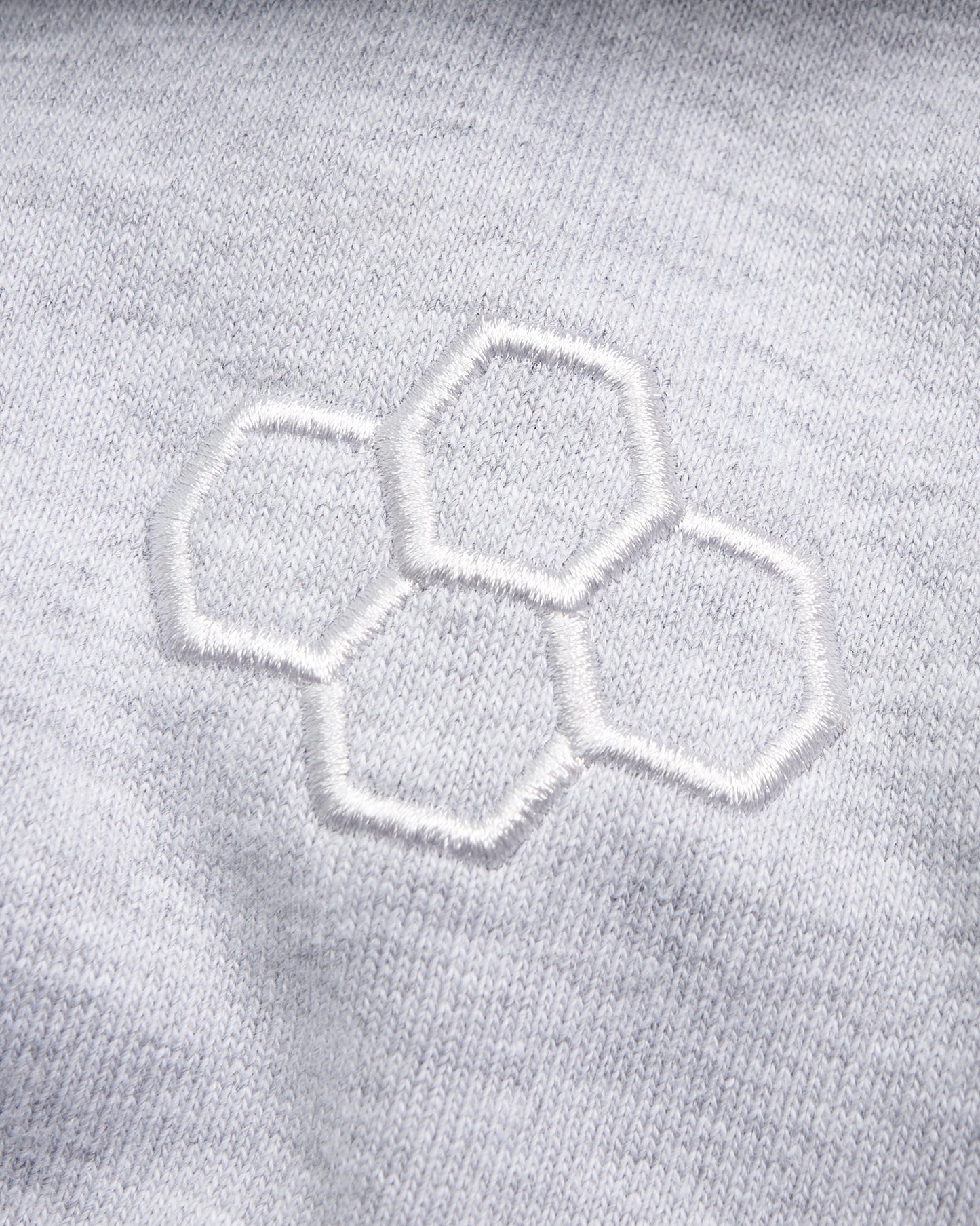 A close-up view of a light gray fabric featuring an embroidered hexagonal pattern showcasing texture and design detail