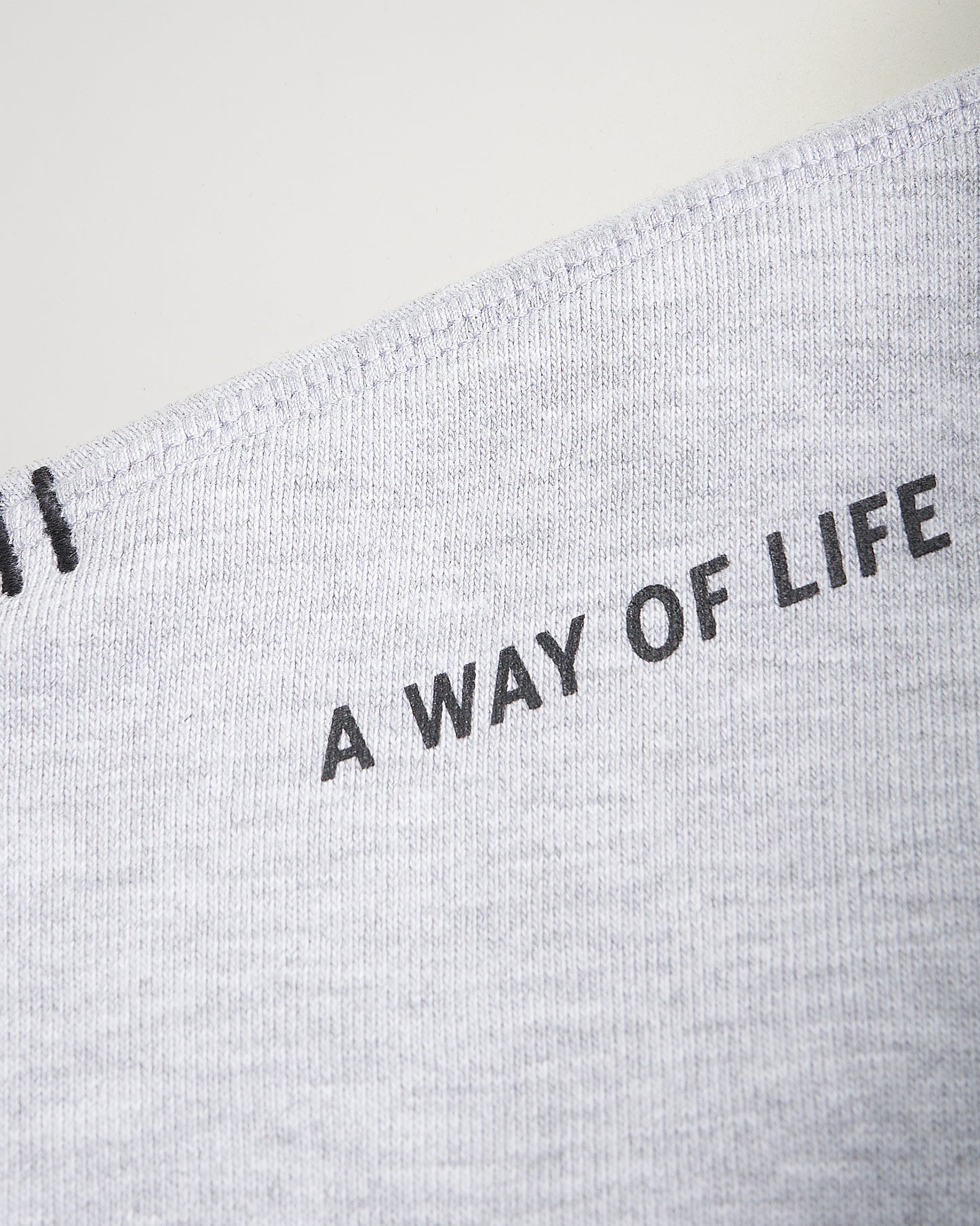 A close-up view of a gray fabric featuring the phrase A WAY OF LIFE printed in bold black letters showcasing the texture and stitching of the material