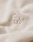 Close-up of a soft beige fabric with a delicate embroidered pattern of interconnected circles, showcasing a minimalist design that enhances its elegance.