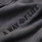 Close-up of dark gray fabric with soft texture displaying 'A WAY OF LIFE' embroidered in a modern font, highlighting a stylish aesthetic.