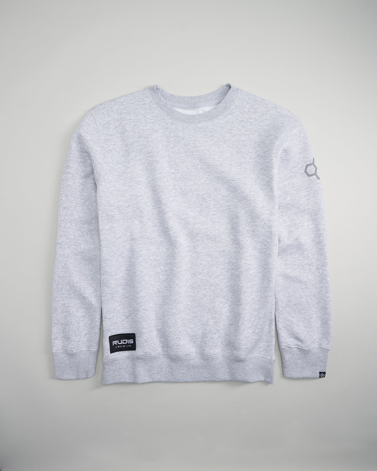 A light gray crewneck sweatshirt featuring ribbed cuffs and a prominent logo patch on the front hem