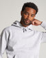 A fashionable black man confidently poses in a light gray hoodie showcasing a casual yet stylish look complemented by his neat haircut and subtle earring