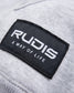 Close-up of a label featuring the brand name RUDIS and the tagline A WAY OF LIFE on a light gray fabric background