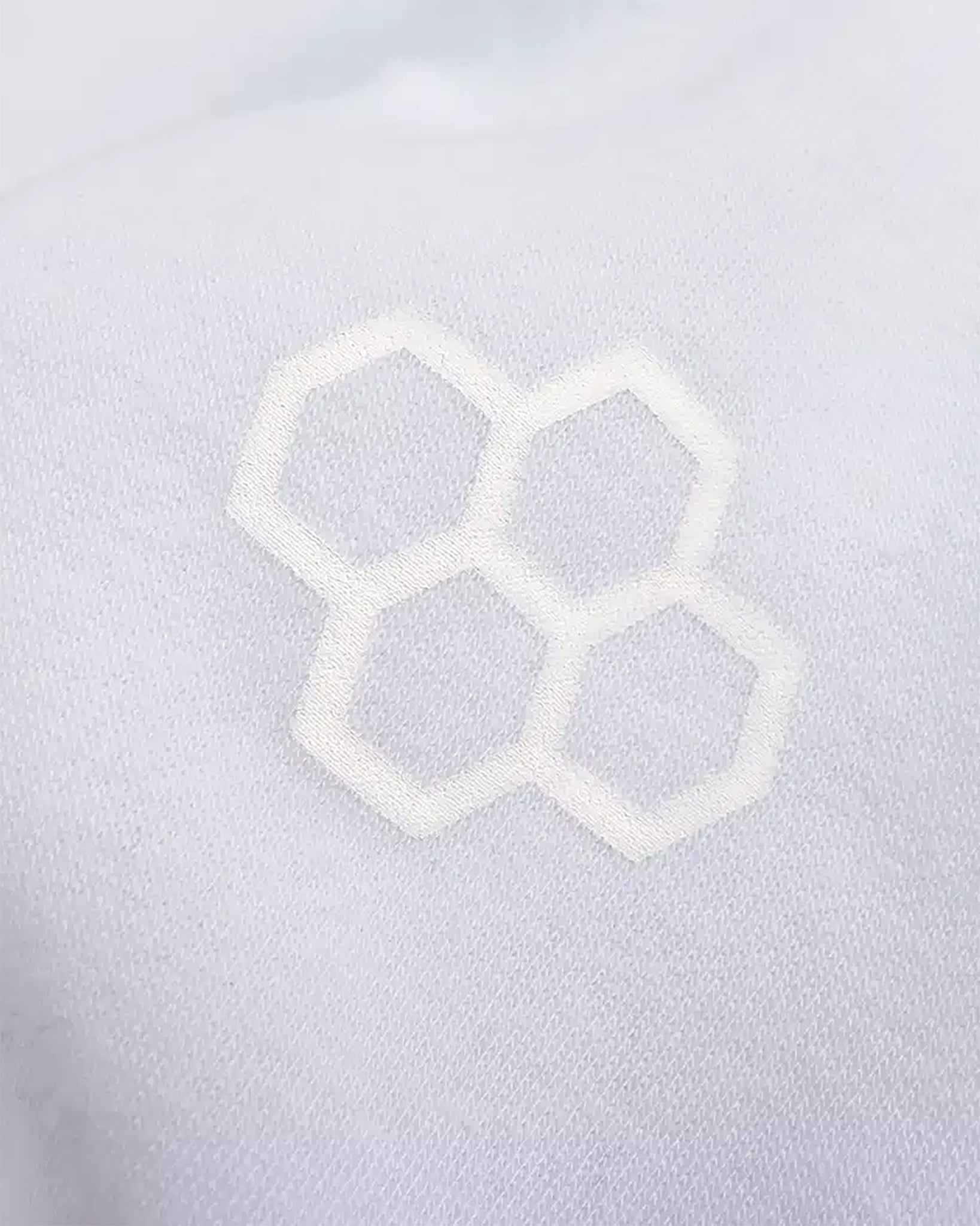 A close-up detail of a white fabric featuring an embossed honeycomb pattern showcasing craftsmanship and design aesthetics