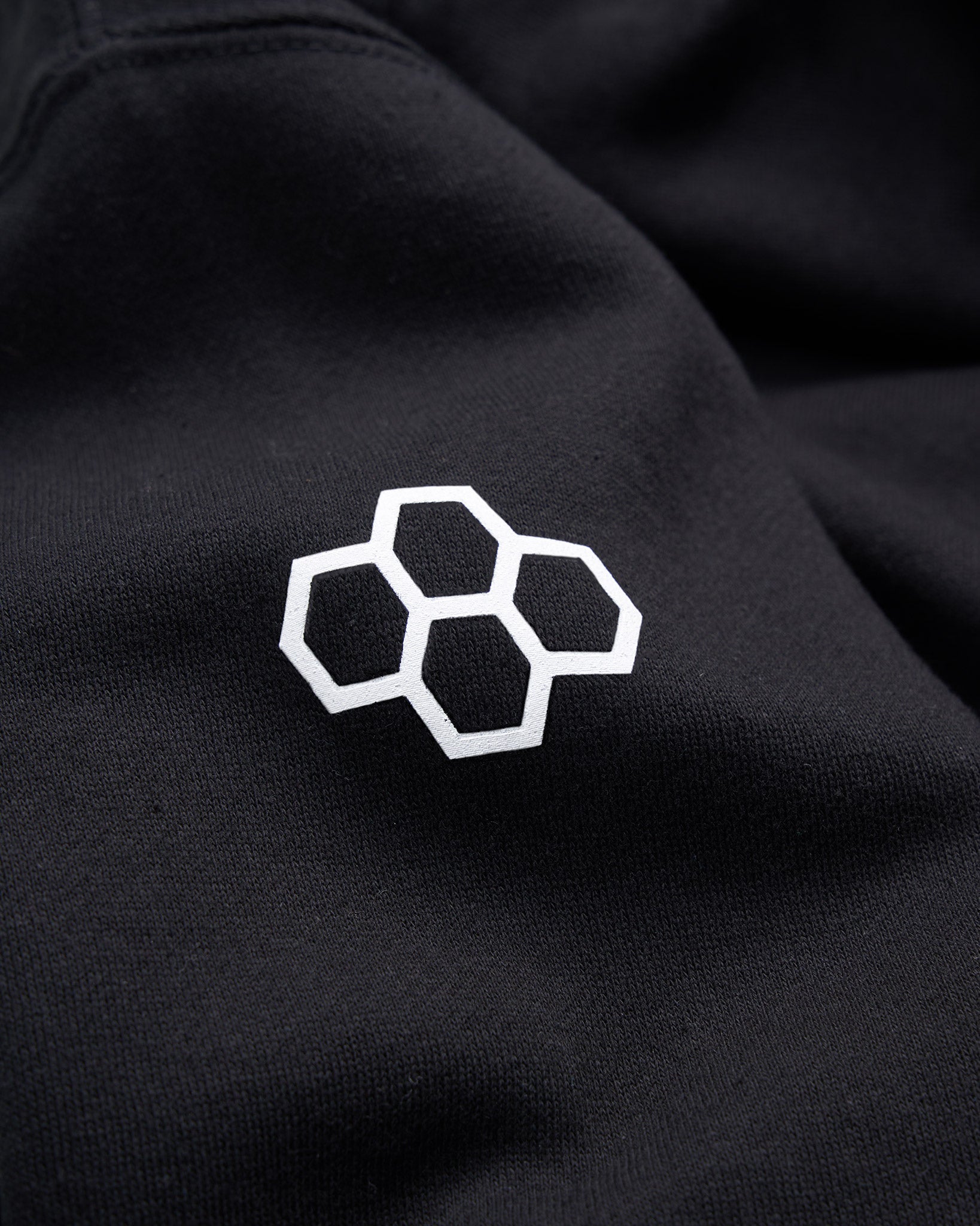 A close-up of a black fabric featuring a white hexagonal logo design emphasizing texture and color contrast