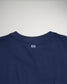 The image displays the back of a navy blue t-shirt prominently featuring a minimalist white design at the neckline