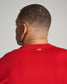 A close-up view of a man wearing a vivid red t-shirt showcasing details of the shirts neckline and a minimalistic design element at the back