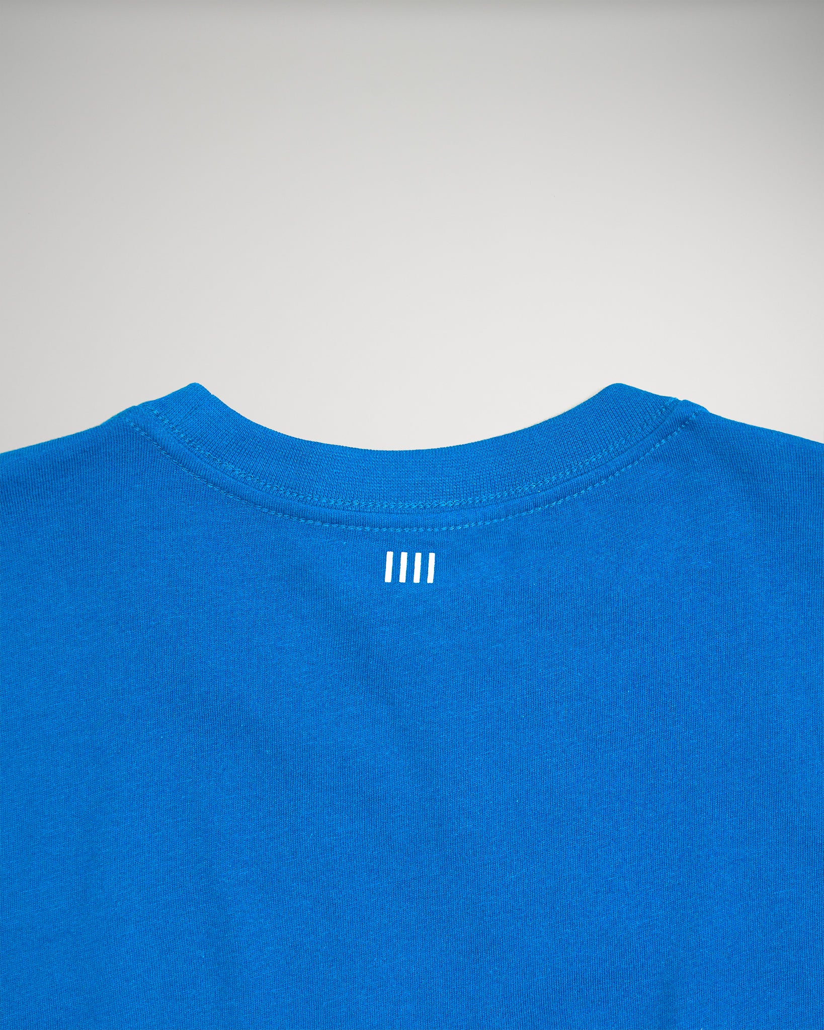 A vibrant blue t-shirt featuring a minimalistic white logo on the back near the collar