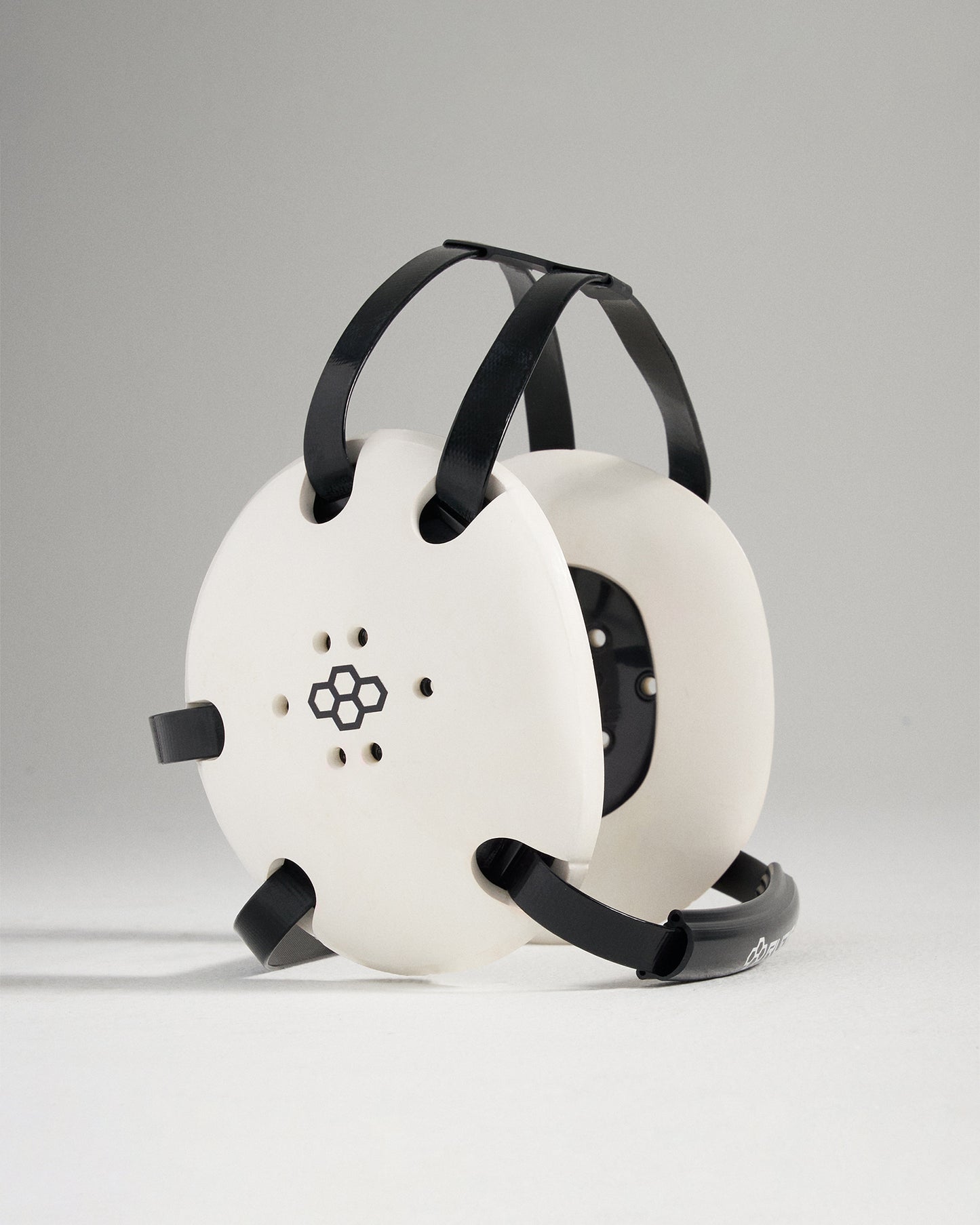 A modern minimalist white and black device with a circular design and straps possibly a unique headphones or audio device