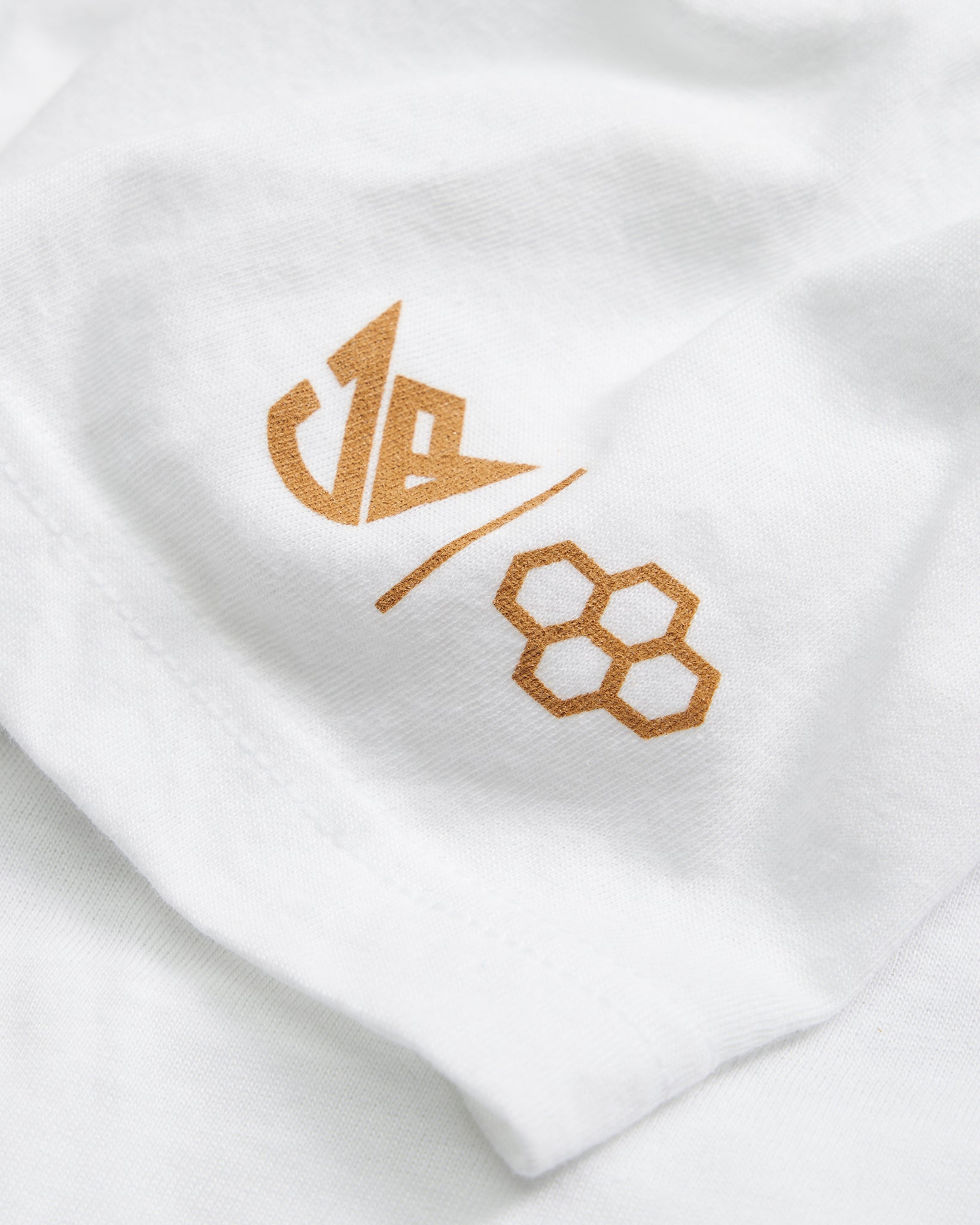 A close-up of a white fabric featuring a stylish gold logo and numbers showcasing contemporary branding design