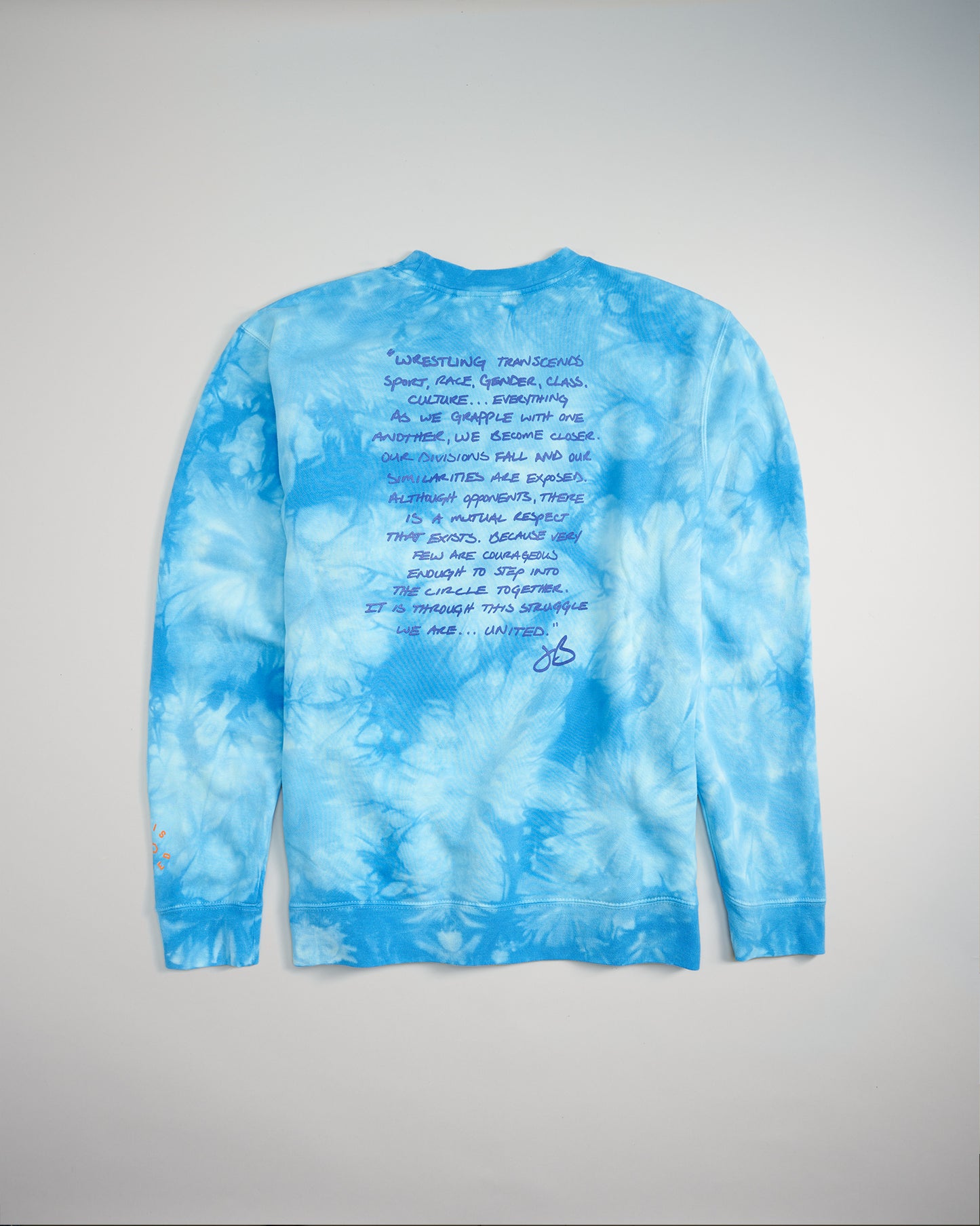 A long-sleeve blue tie-dye shirt featuring handwritten text that addresses themes of unity and cultural challenges