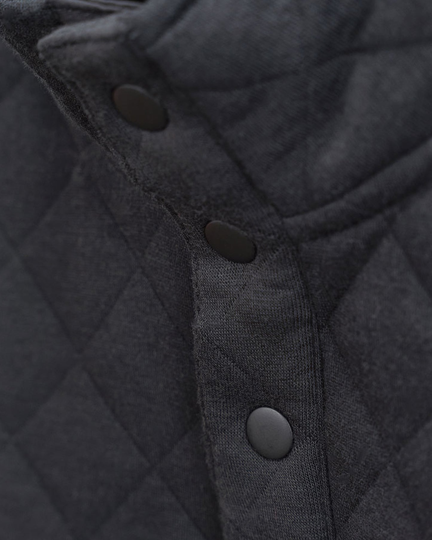 Close-up view of a black quilted fabric with snap buttons showcasing a textured pattern and stitching details